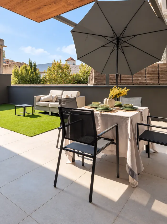 Terrasse avec gazon, table d’extérieur et parasol